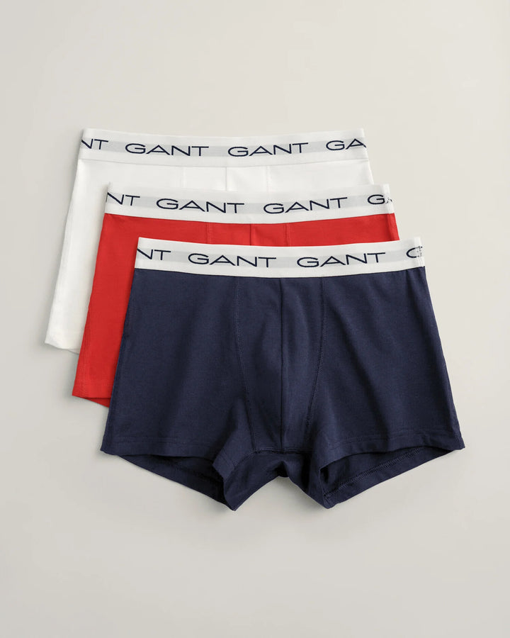 A pack of three GANT branded men's trunks in white, red, and navy colors, displayed flat.
